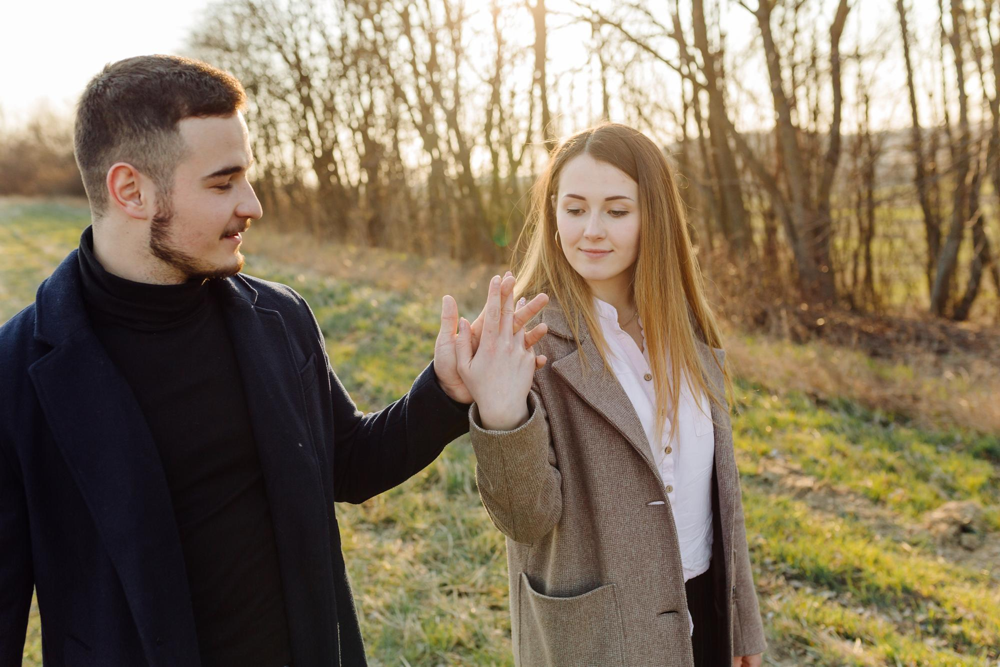 A happy couple walks hand in hand through a sunlit park on a spring day, smiling, capturing the emotional joy, reconnection, and renewed intimacy that couples experience during a retreat.