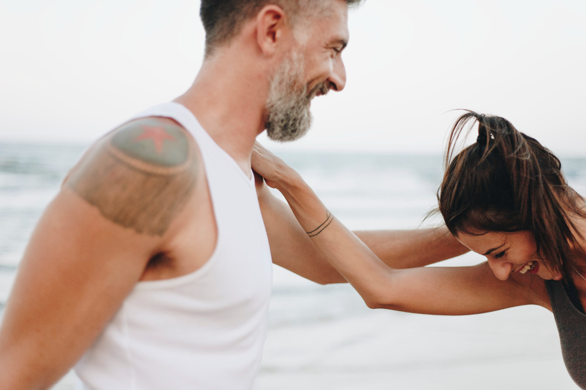 A romantic couple stretching by the sea, enjoying a serene retreat—a perfect example of emotional intelligence in relationships through shared mindfulness and connection.