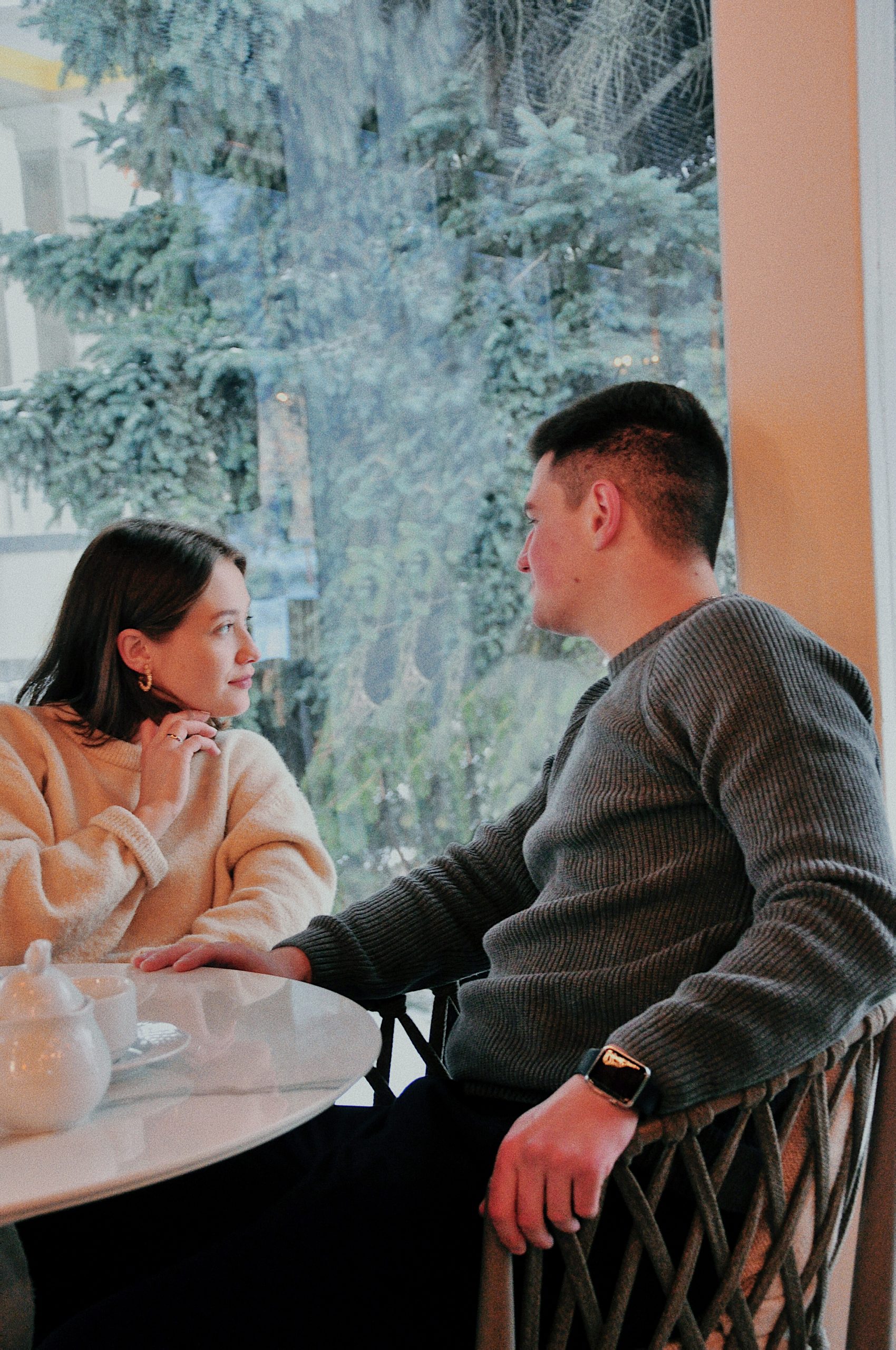 A cheerful couple enjoying a relaxed conversation at a sunny restaurant table, illustrating the bonding, teamwork, and renewed communication that marriage retreats aim to strengthen.