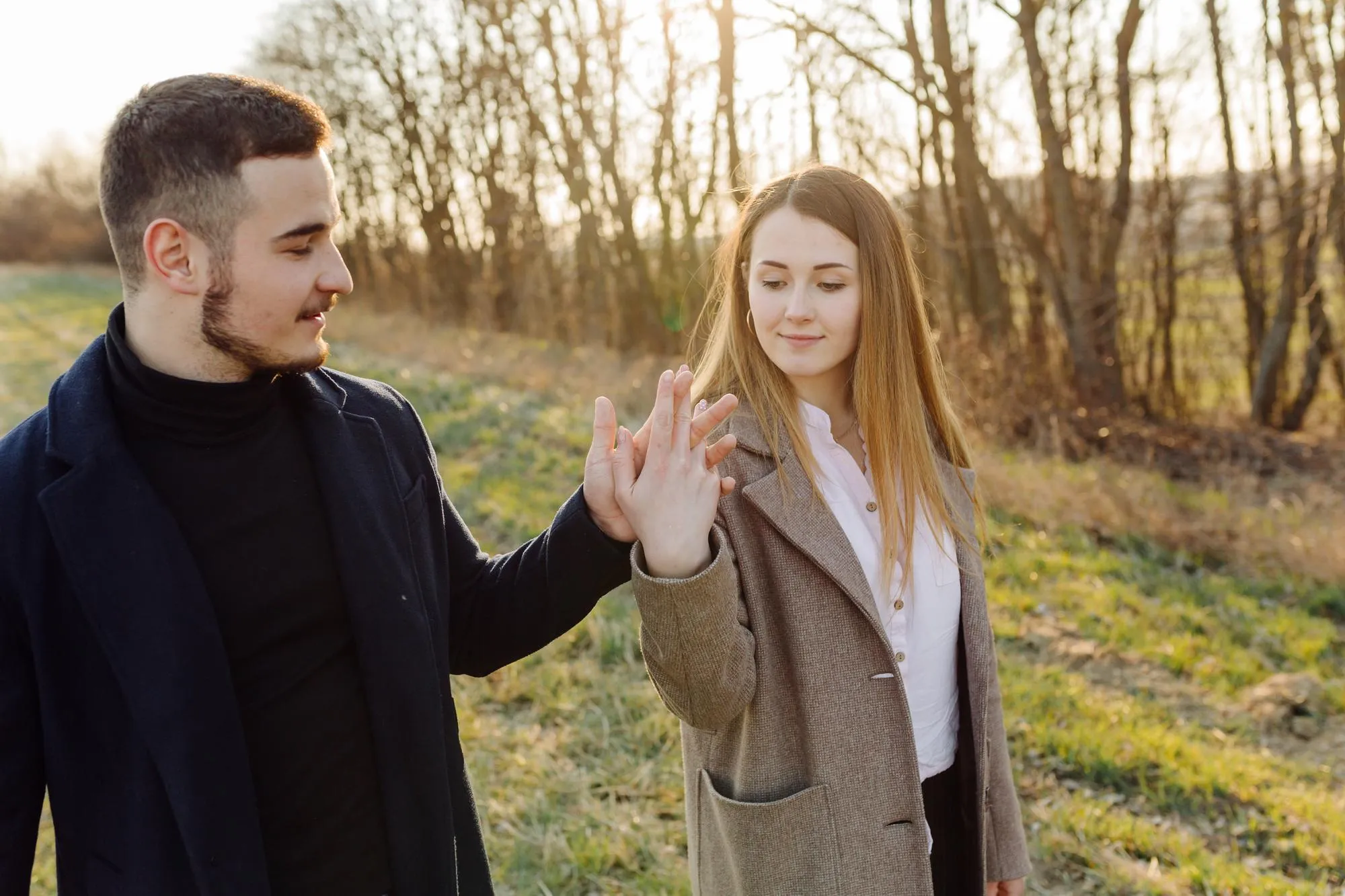 A happy couple walks hand in hand through a sunlit park on a spring day, smiling, capturing the emotional joy, reconnection, and renewed intimacy that couples experience during a retreat.