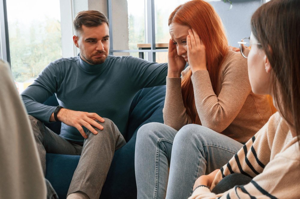 A couple working through the early stages of healing after infidelity, with the woman visibly upset and the man showing concern during a counseling session.