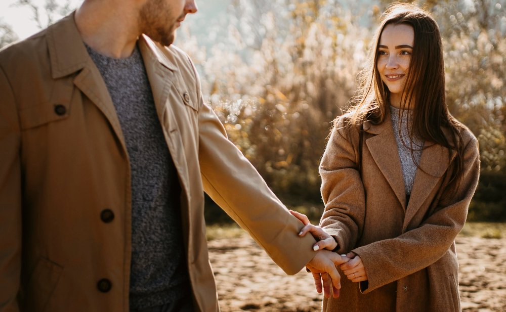 A couple holding hands outdoors, sharing a gentle moment while navigating differences in their relationship.