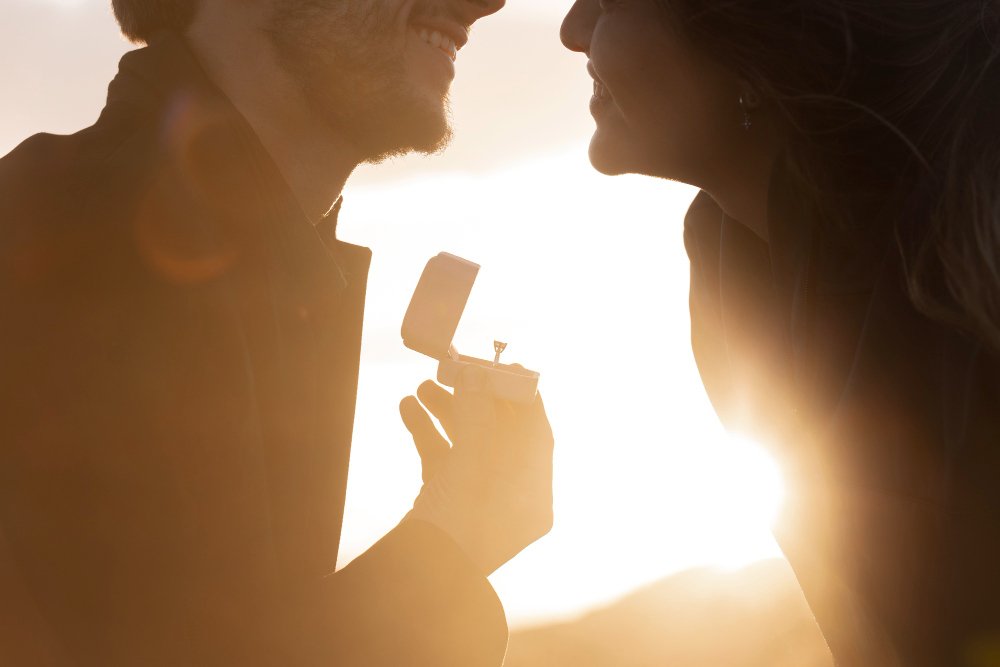 A couple sharing an intimate moment during a proposal at sunset, symbolizing big relationship decisions and navigating different wants for the future.
