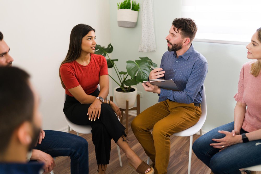 Licensed counselor taking notes while listening to clients during a therapy session
