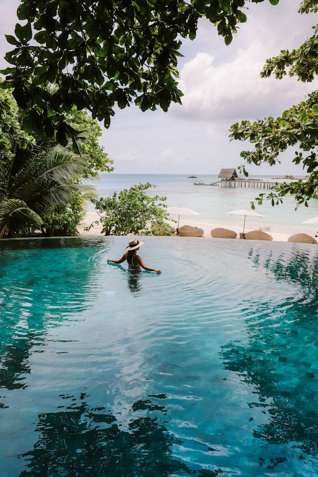Woman relaxing in a luxury, private resort pool right next to the ocean 
