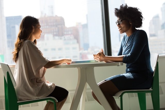 Two women seated at a table in a focused conversation