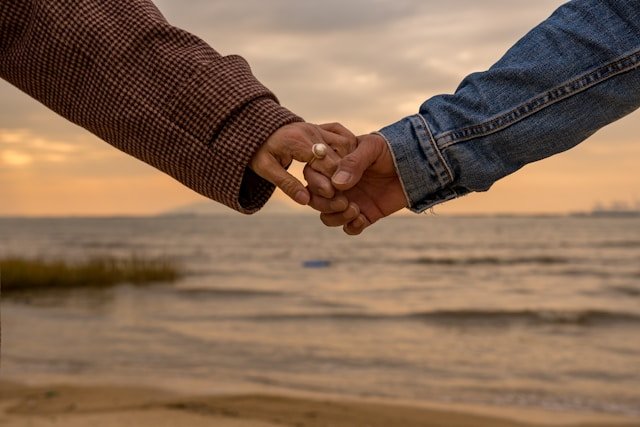 Couple holding hands on the beach, reflecting trust and emotional connection
