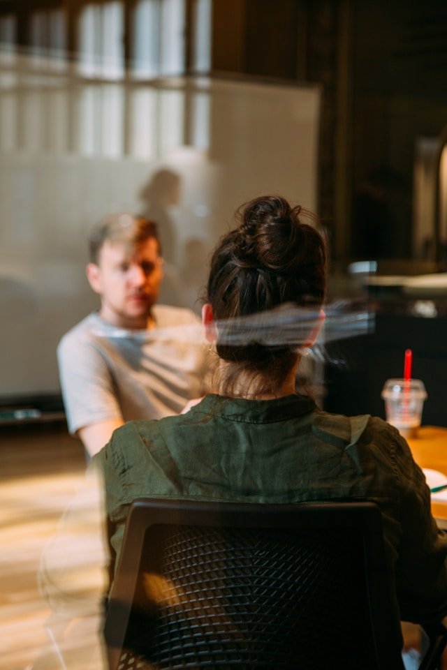 One person listening carefully to another across a table, illustrating the focused attentive one-to-one dialogue of a retreat 
