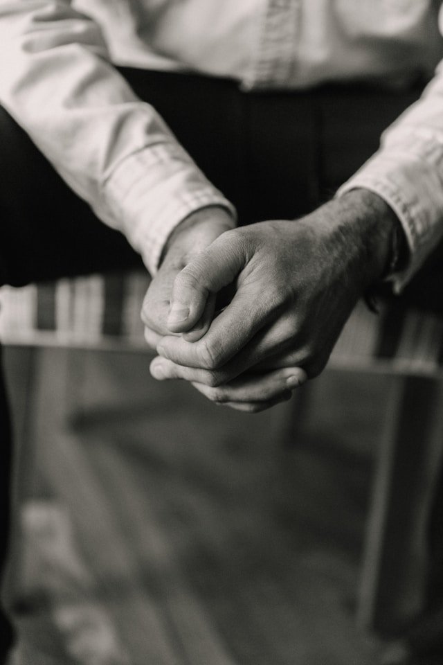 A grayscale close-up of two people holding hands, representing the emotional weight and physical grounding of betrayal trauma