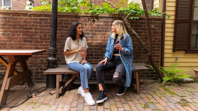 Two women in conversation on a bench outdoors representing the social reconnection that supports empty nest syndrome recovery 
