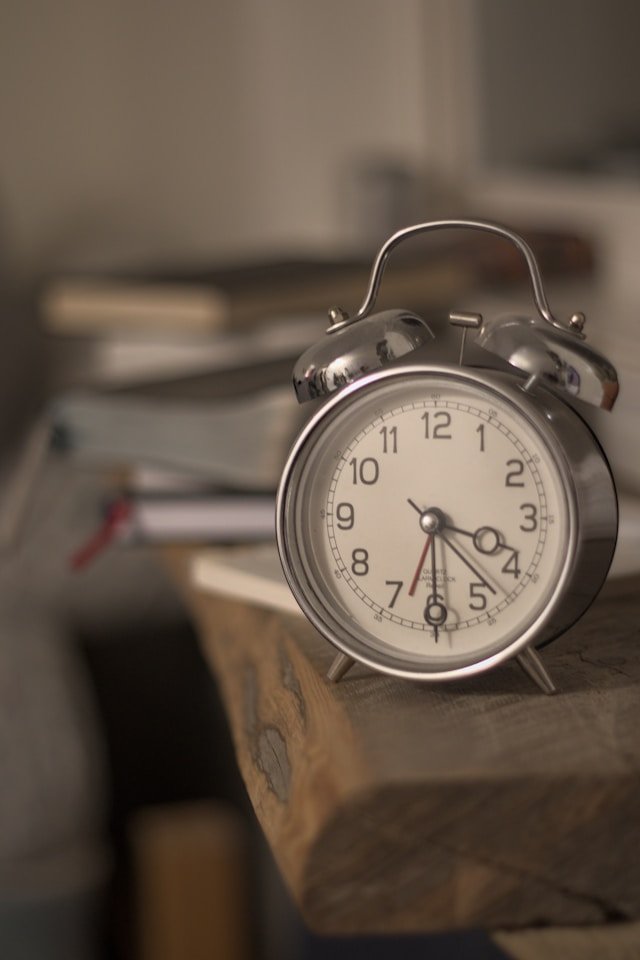 An alarm clock on a wooden desk, representing the strict time limits of weekly couples therapy and why some couples need more
