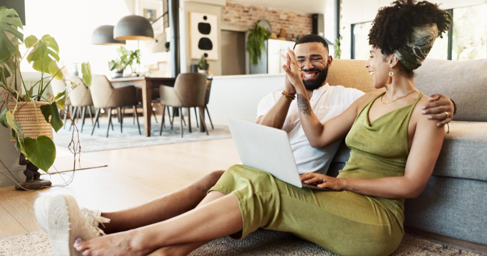 A couple sitting on the floor with a laptop, exploring whether couples retreats work.