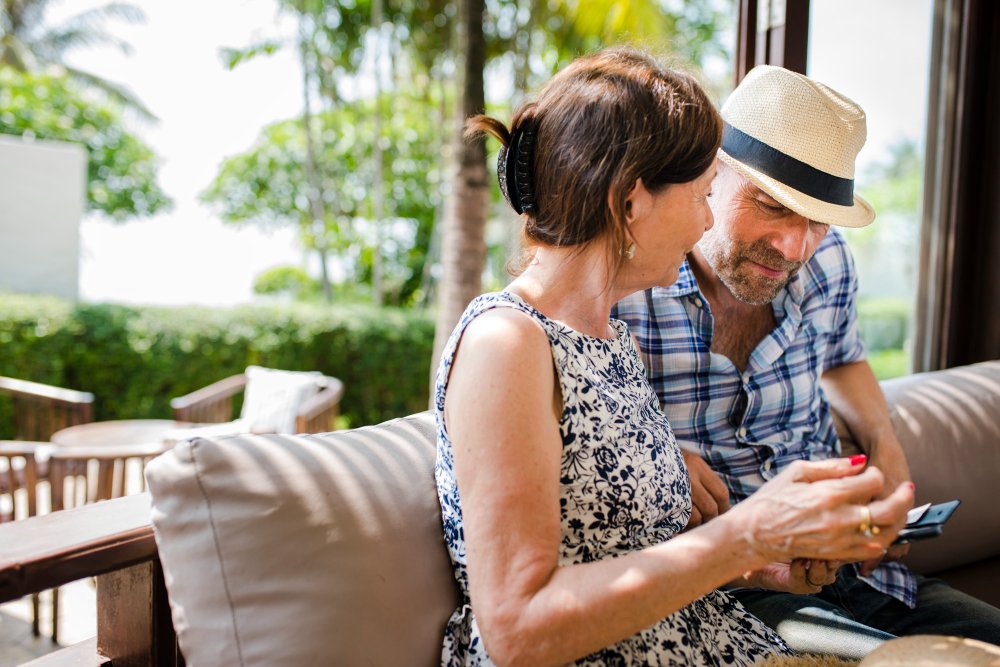 A couple looking at a phone together on a patio sofa, enjoying a private couples retreat.