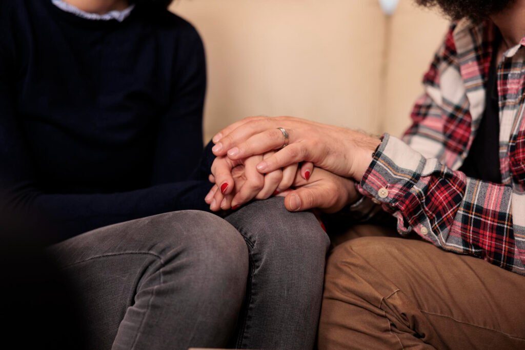 Couples retreat support: two people hold hands closely while seated together 