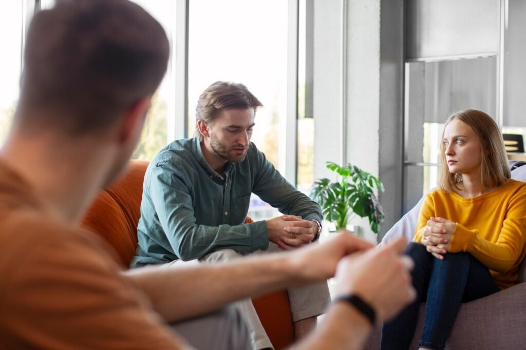 Couples counseling session: a man and woman talk while counselor listens nearby