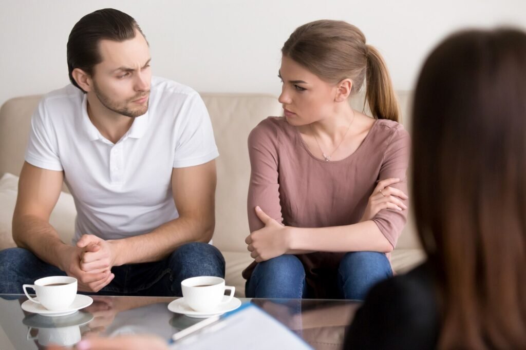 Couples counseling session with tense couple and untouched coffee cups on table 