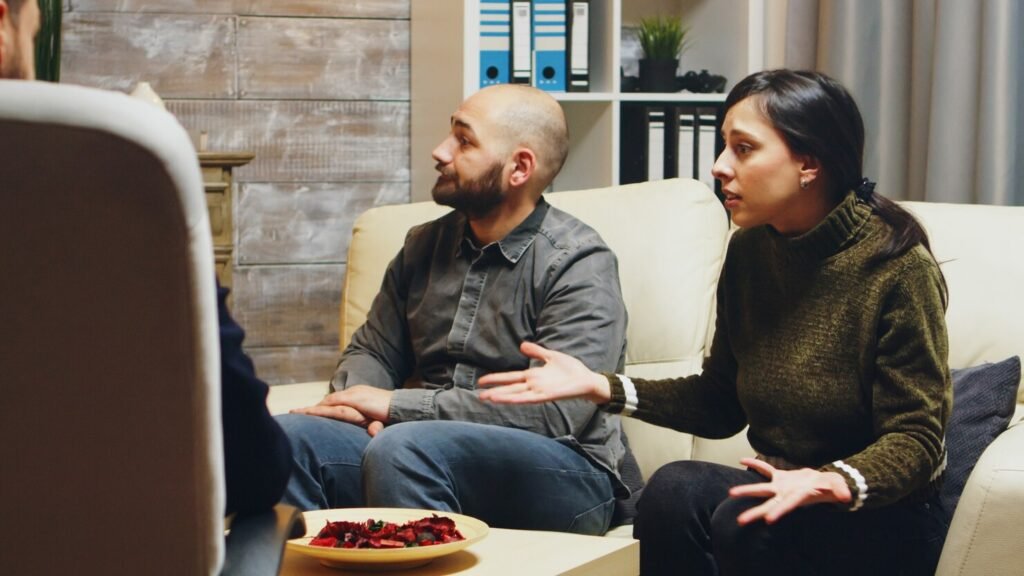 Couples therapy session: woman gestures while explaining as partner listens